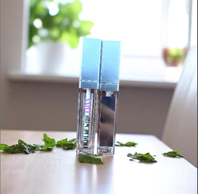 Majestic Mint Lip Gloss with refreshing mint leaves in a bright room setting.