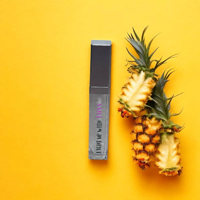 Paradise Pineapple Lip Gloss with pineapple, tropical beauty product on yellow background.